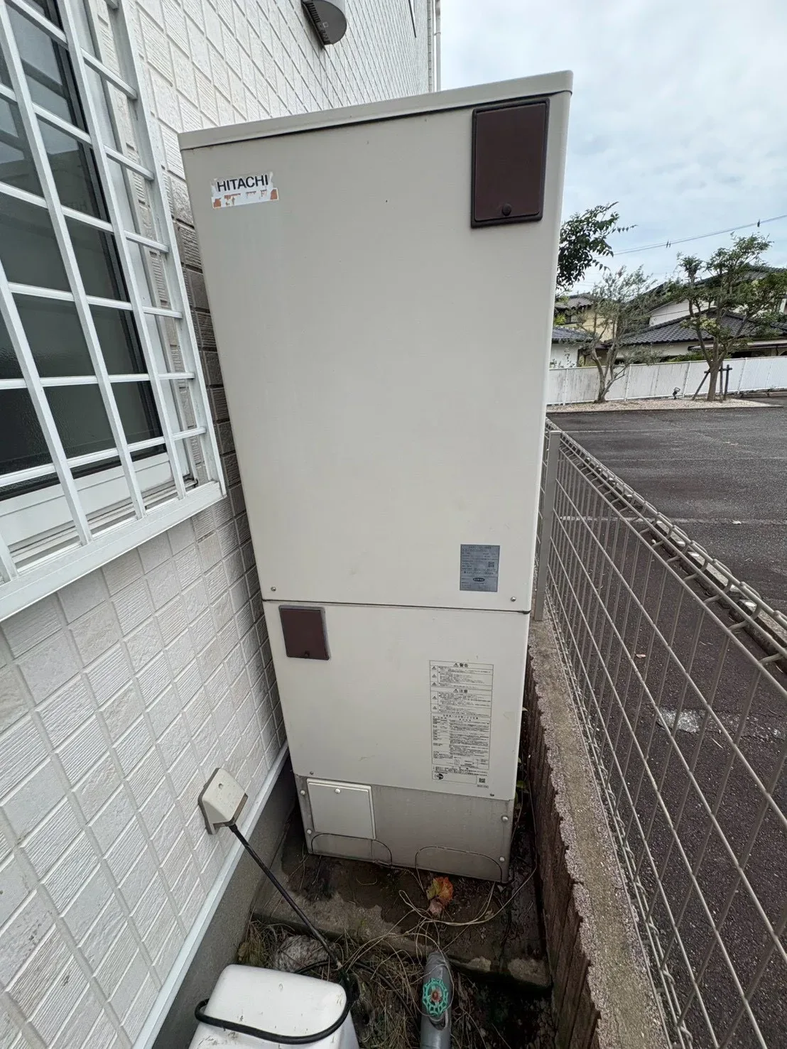 窓の脇に設置されたエコキュートのヒートポンプユニット