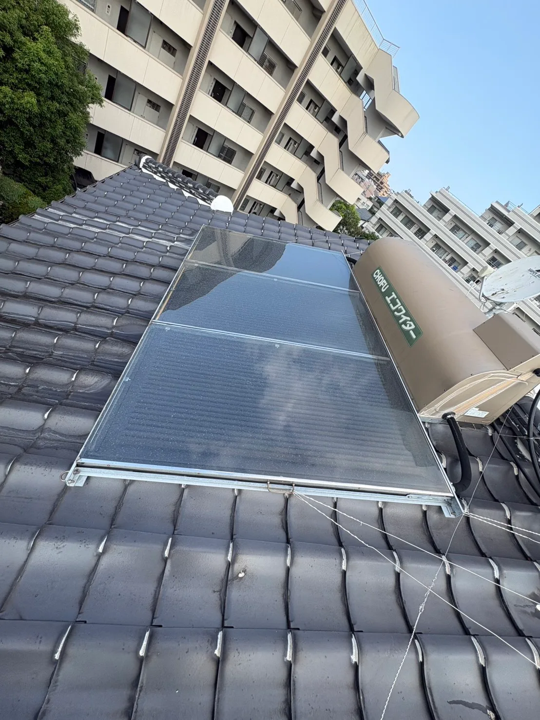 屋根の上に設置された太陽熱温水器のタンクとパネル