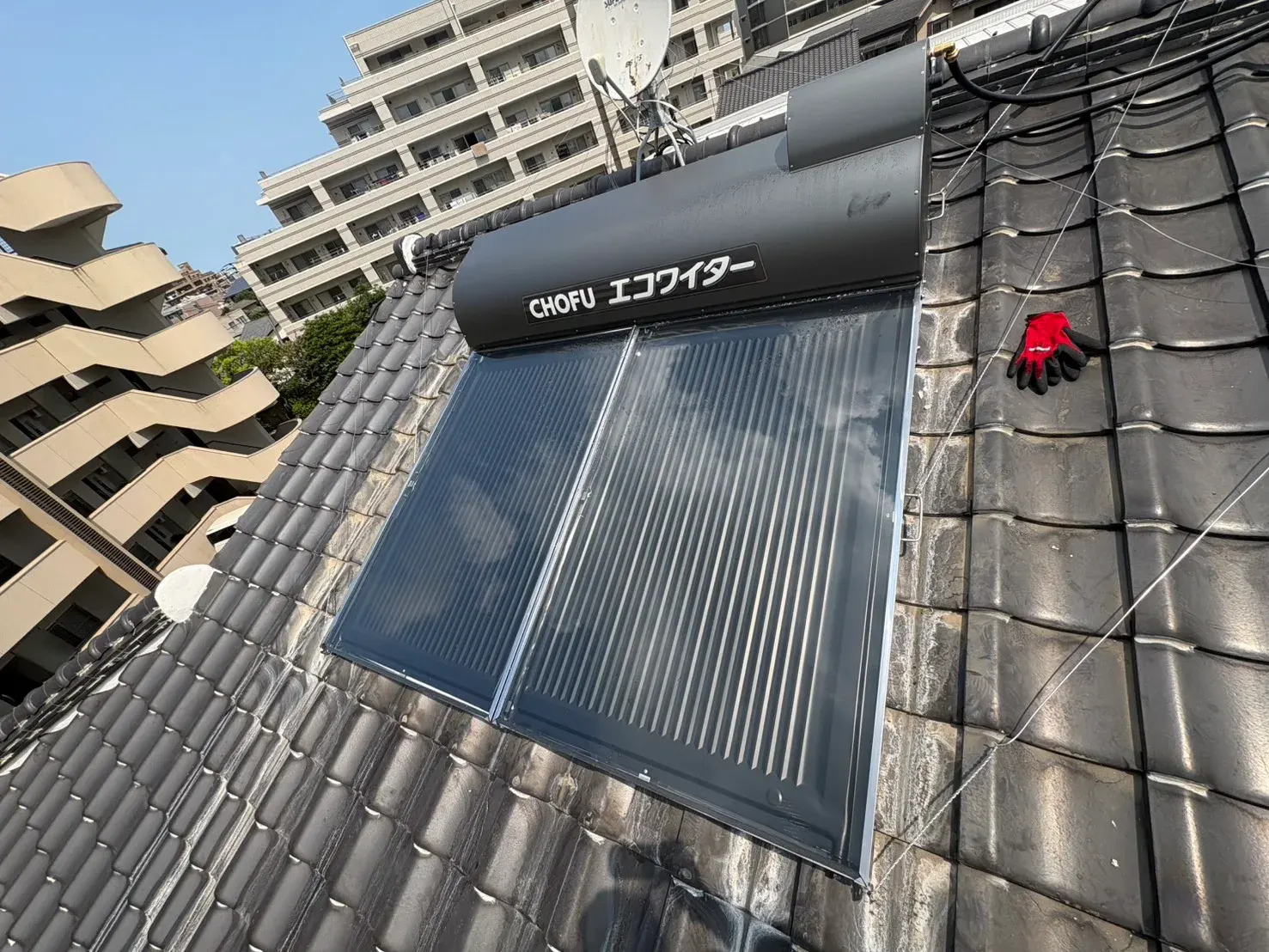 屋根に設置された太陽熱温水器の集熱パネルとタンク