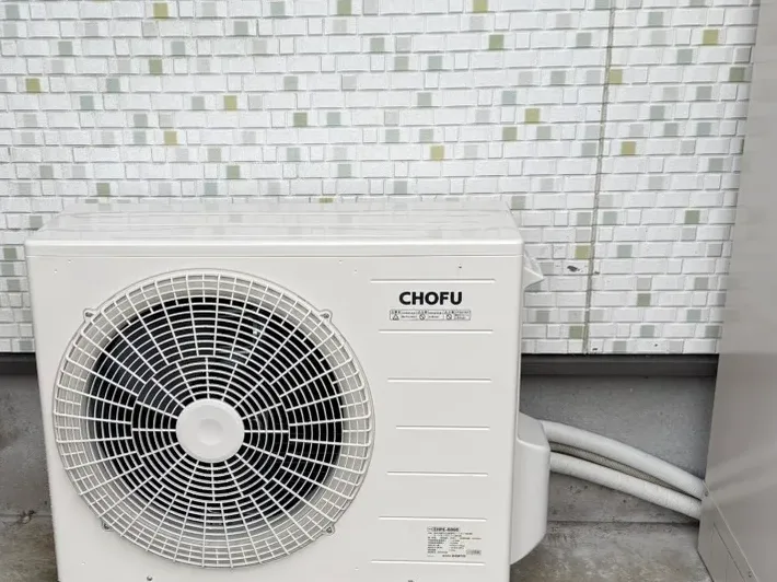 タイル張りの外壁に設置されたCHOFU製ヒートポンプ給湯器の屋外機